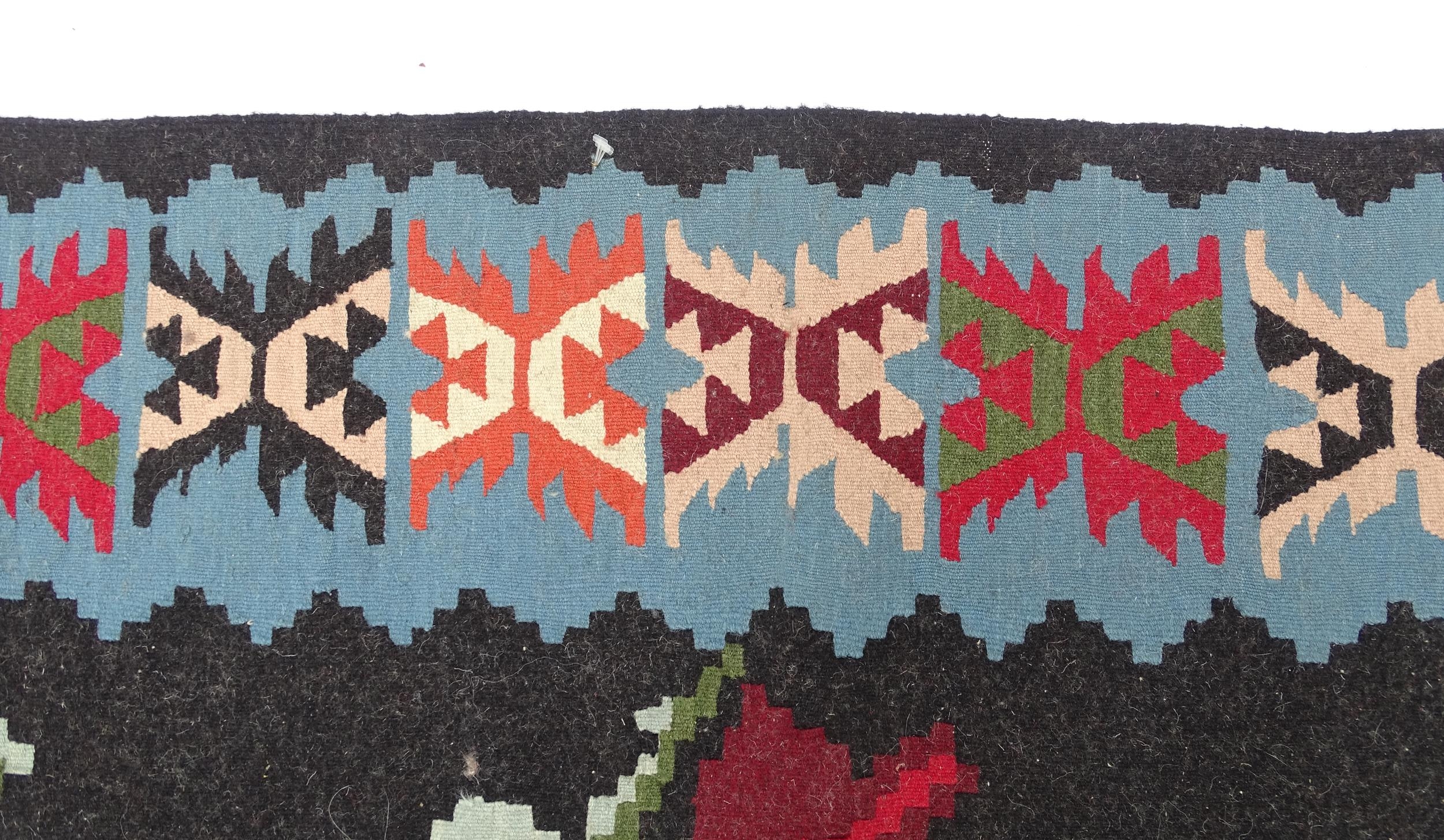 Carpet / Rug : A black ground rug with red floral decoration, with geometric motifs to borders. - Image 6 of 9