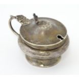 A silver mustard pot with hinged lid and blue glass liner. Hallmarked Birmingham 1923, maker Henry