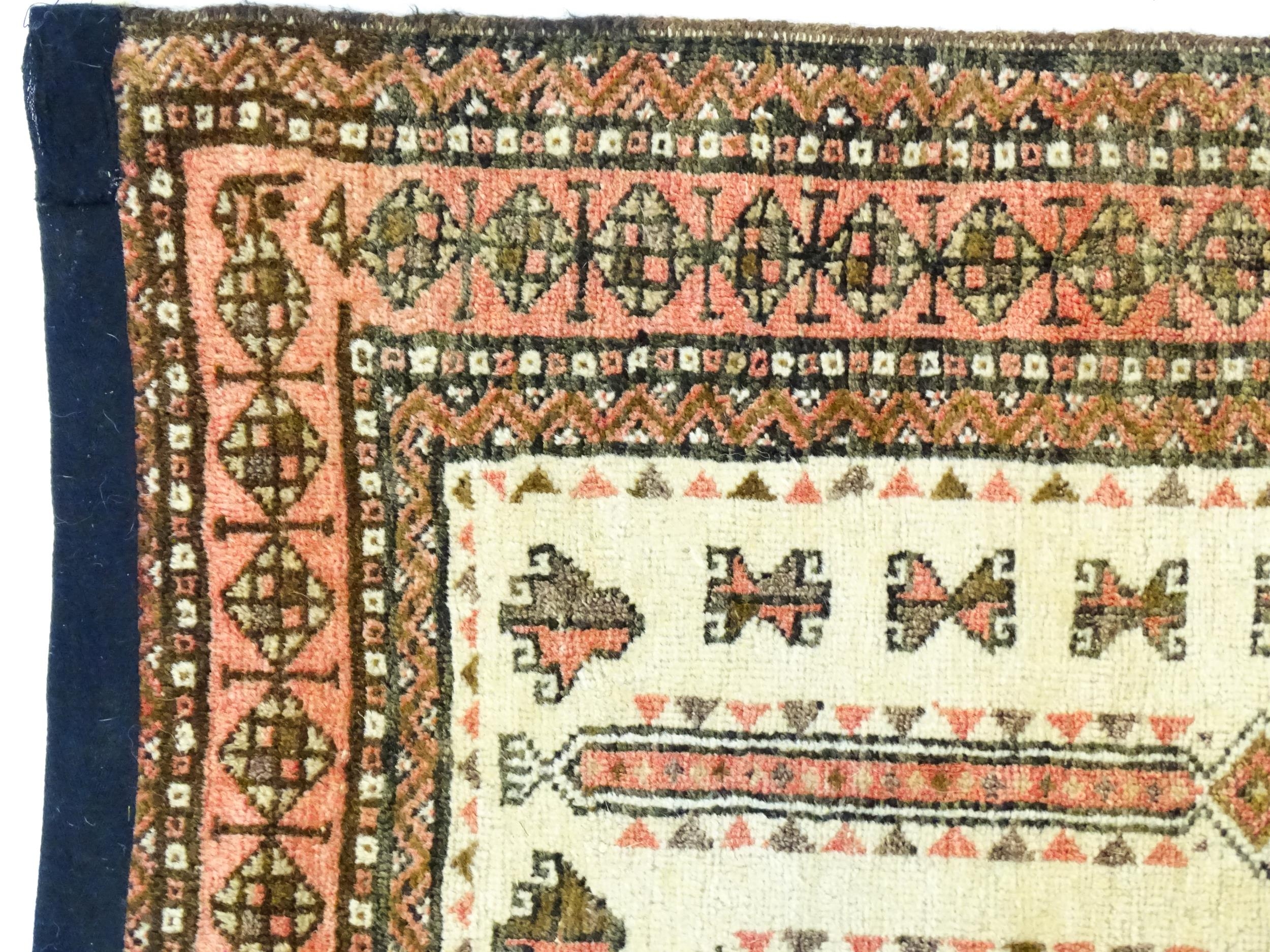 Carpet / Rug: A beige ground rug with repeated motifs worked in salmon pink, brown and beige, with - Image 3 of 9