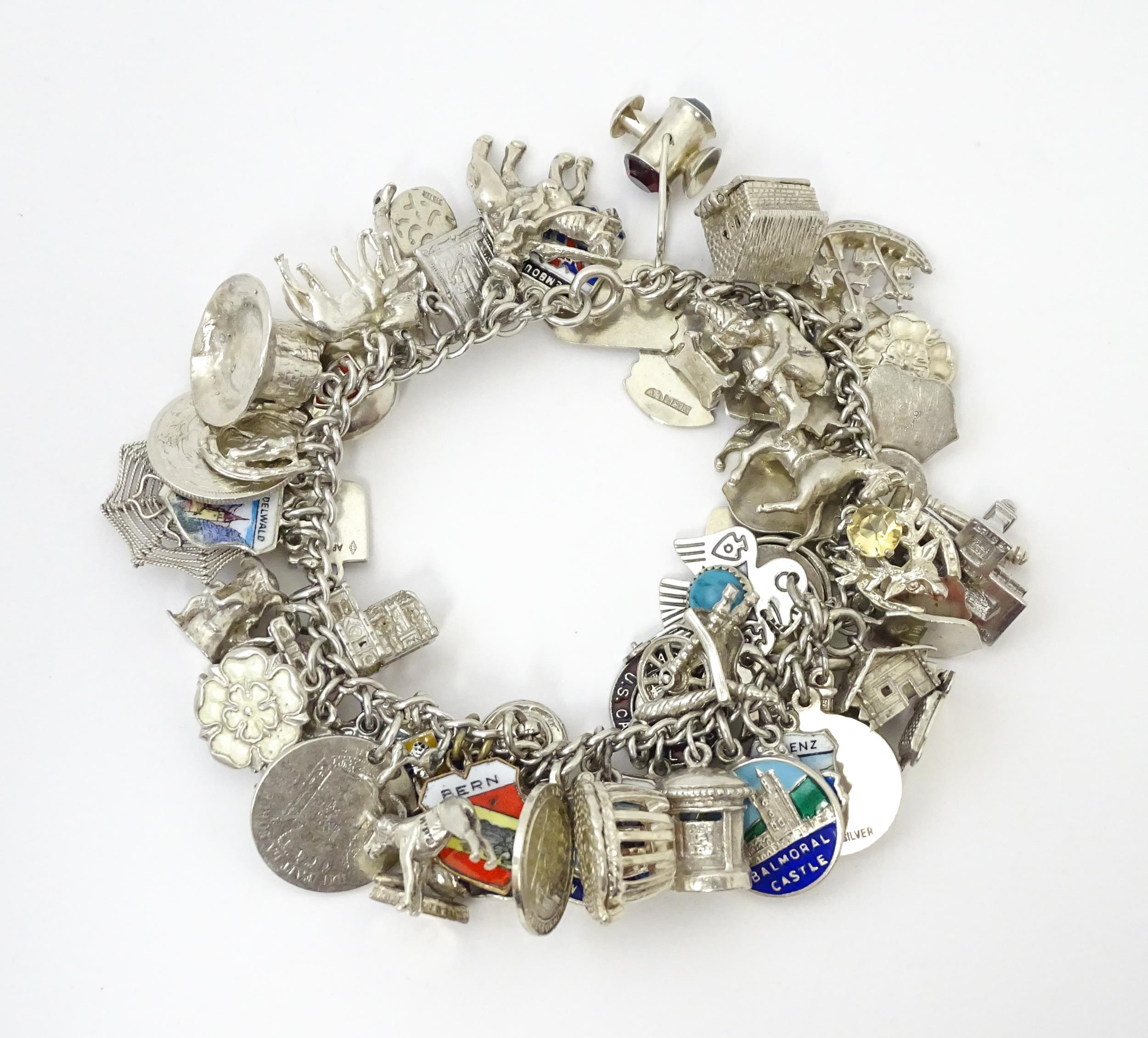 A silver charm bracelet set with various silver, white metal and silver plate charms Please Note -