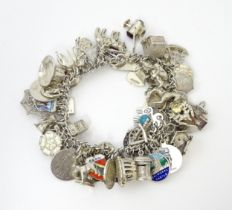A silver charm bracelet set with various silver, white metal and silver plate charms Please Note -