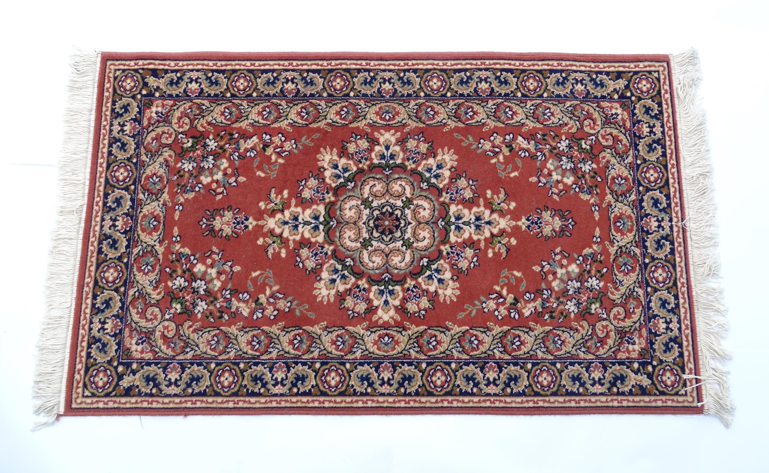 Carpet / Rug : A red ground rug with central floral motif, bordered by floral and foliate scroll