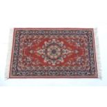 Carpet / Rug : A red ground rug with central floral motif, bordered by floral and foliate scroll