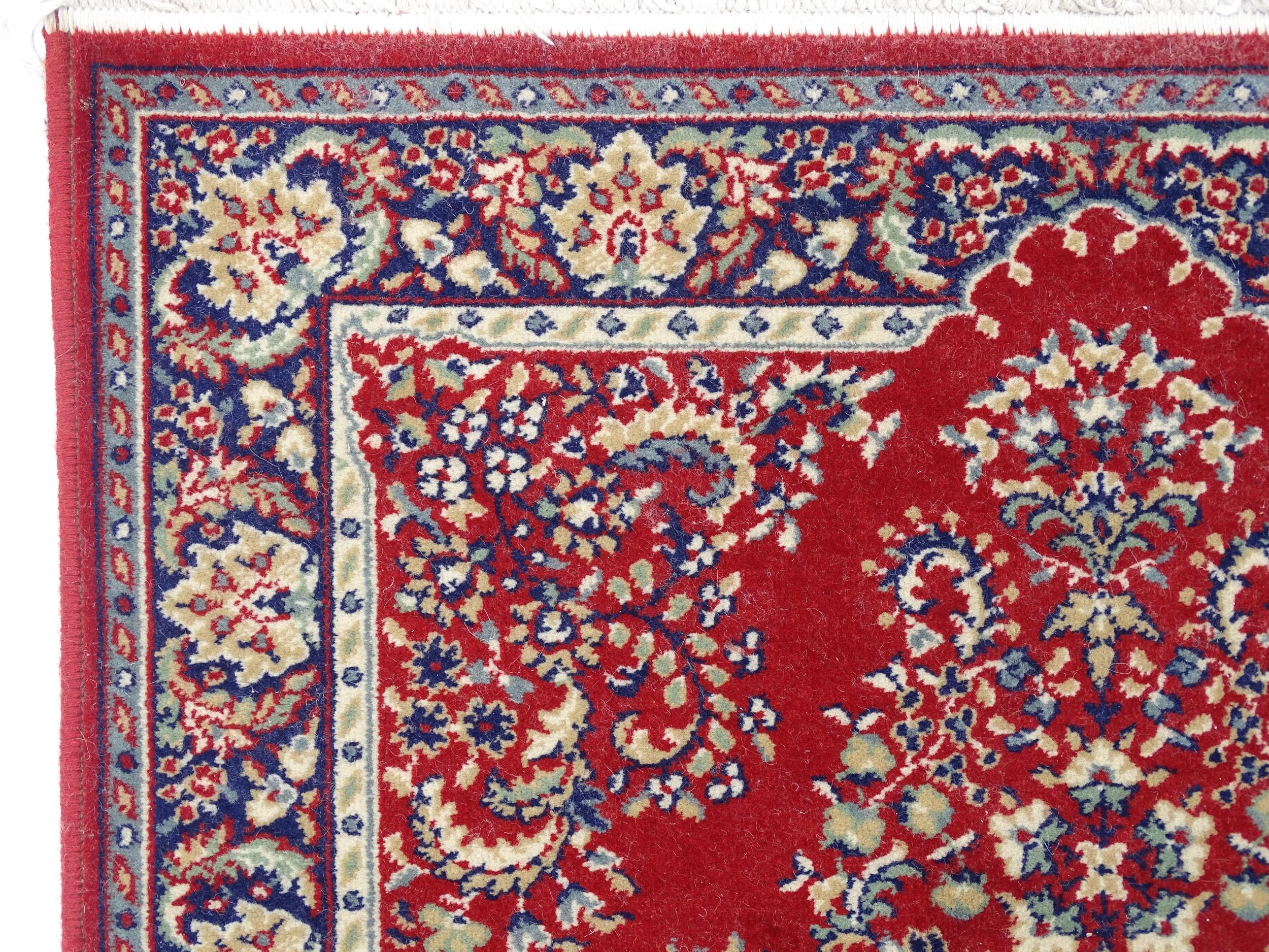 Carpet / Rug : A red ground rug with central cream and blue vignette, decorated with floral and - Image 3 of 6