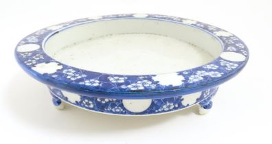 A Chinese blue and white stand of circular form raised on three feet decorated with prunus