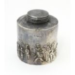 A silver tea caddy depicting a village scene with buildings and figures. Hallmarked Chester c.