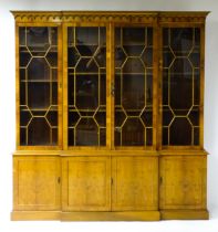 A yew wood veneered bookcase with a moulded cornice above four astragal glazed doors containing