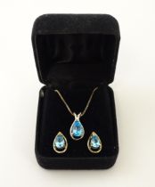 A silver necklace with pendant set with topaz, together with matching stud earrings. Chain approx.