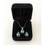 A silver necklace with pendant set with topaz, together with matching stud earrings. Chain approx.