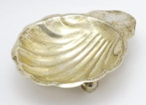 A Mexican sterling silver butter dish of scallop shell form raised on three ball feet, maker Juvento