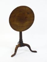 A late 18thC / early 19thC mahogany tripod table with a circular tilt top above a turned pedestal