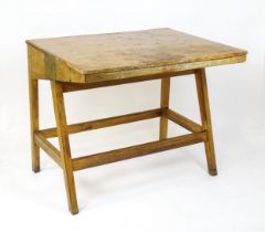 A mid / late 20thC artists desk with a hinged, adjustable top raised on tapering legs united by a