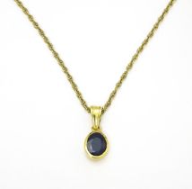 A yellow metal pendant set with central sapphire on a 9ct gold chain. Pendant approx. 1 3/4" long