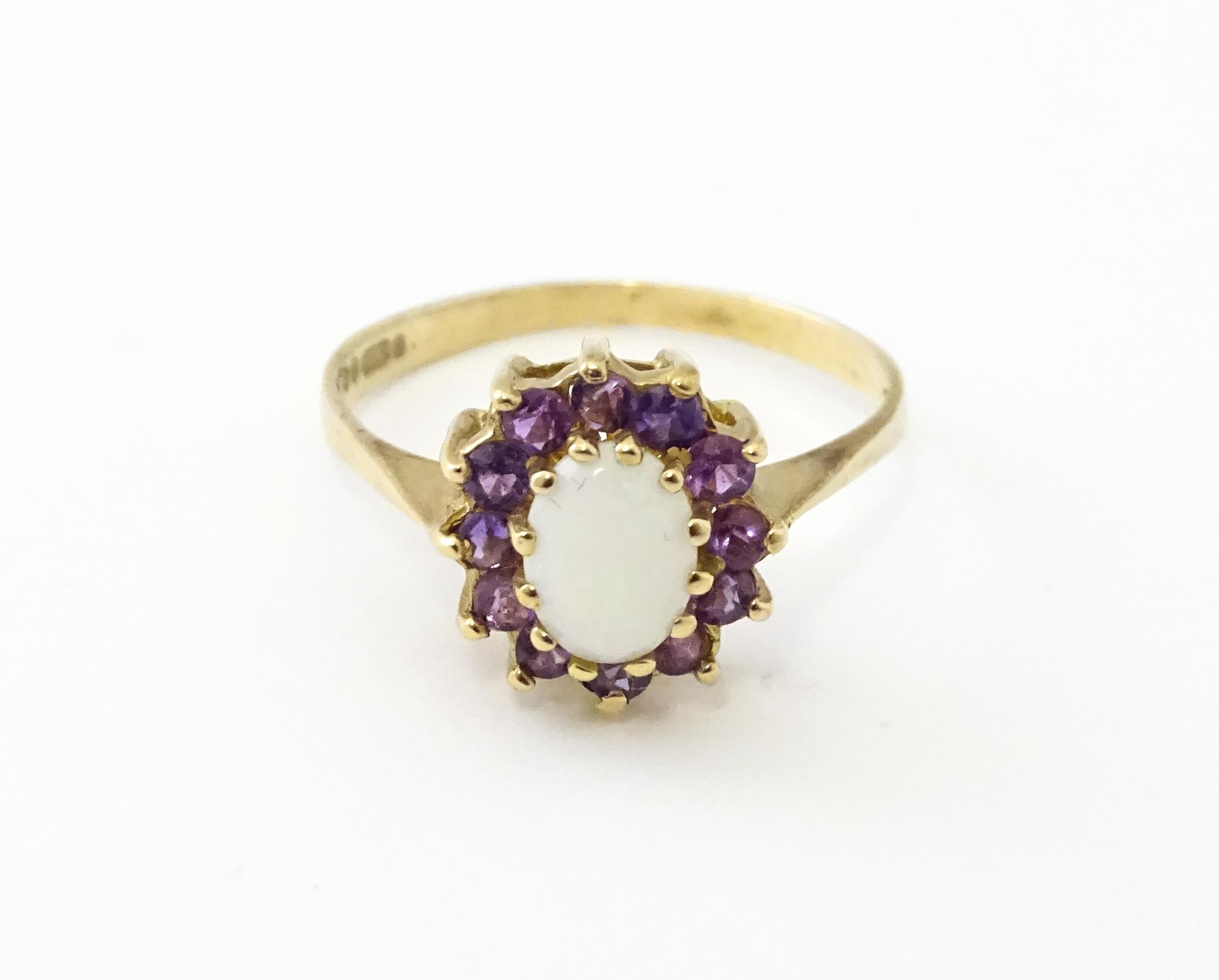 A 9ct gold ring set with central opal bordered by amethysts. Ring size approx. M Please Note - we do