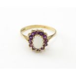 A 9ct gold ring set with central opal bordered by amethysts. Ring size approx. M Please Note - we do