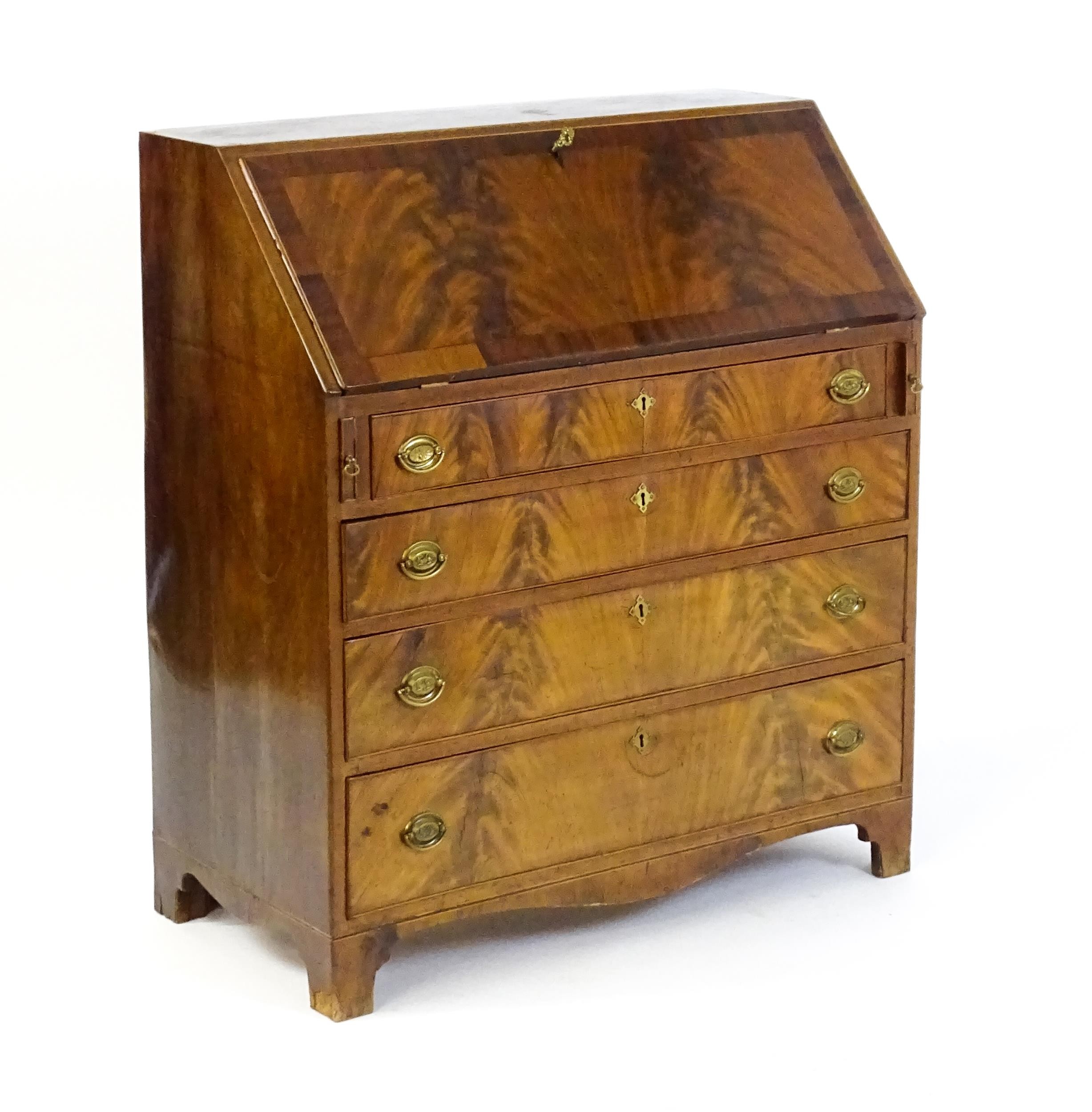 An early 19thC mahogany bureau with a fall front above four long graduated drawers with brass back