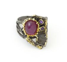 A silver ring set with ruby cabochon and two amethysts, with gilt highlights. Ring size approx. O