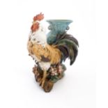 A Continental model of a cockerel / rooster with a blue vase with twin loop handles. Approx. 11 3/4"
