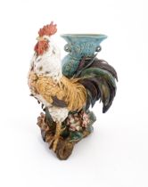 A Continental model of a cockerel / rooster with a blue vase with twin loop handles. Approx. 11 3/4"