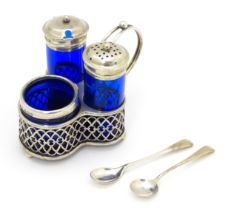 A silver cruet set with blue glass bottles, comprising stand, salt, pepper and mustard, hallmarked