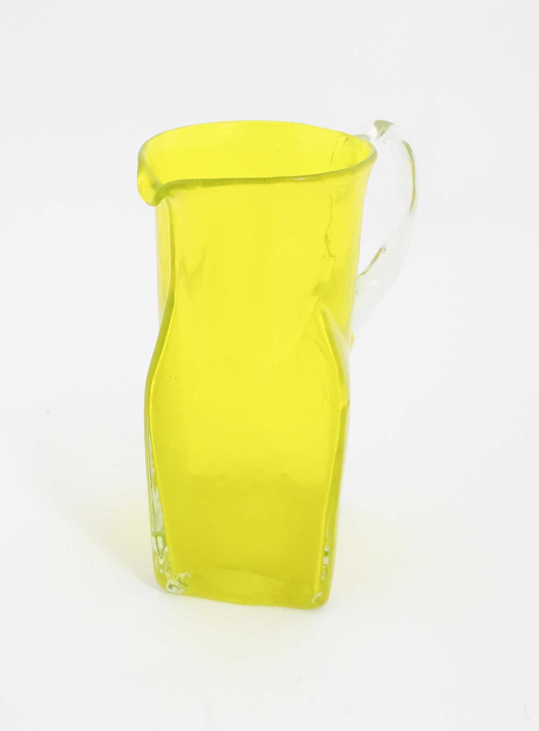 A 20thC yellow glass jug with squared base and clear glass handle. Approx. 8 1/2" high Please Note -