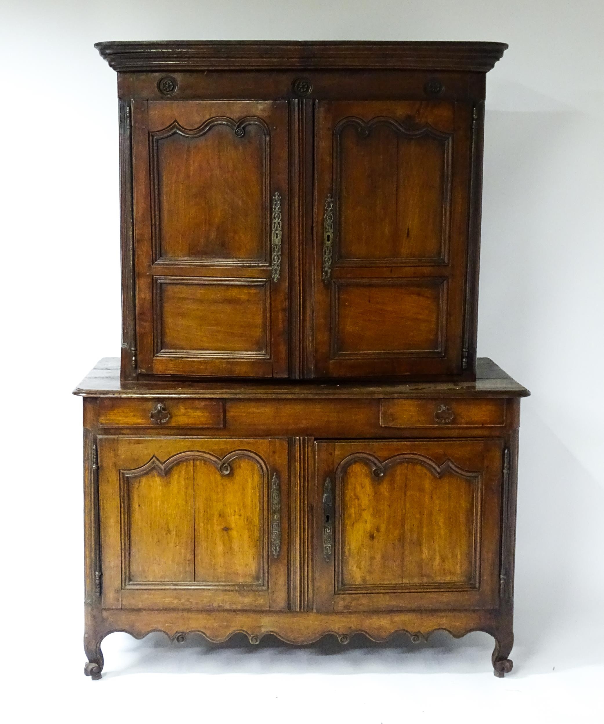 An 18thC French buffet deux corps with a moulded pediment above a floral carved frieze. The top