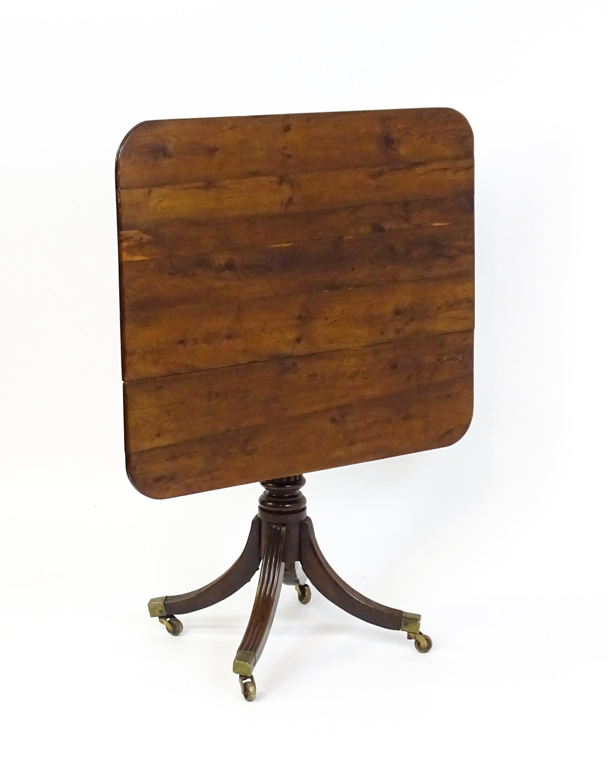 A 19thC tilt top occasional table with yew wood planked top above a reeded mahogany pedestal and