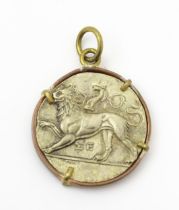 A white metal pendant with lion detail to one side, and dove to the other. Within a brass and copper