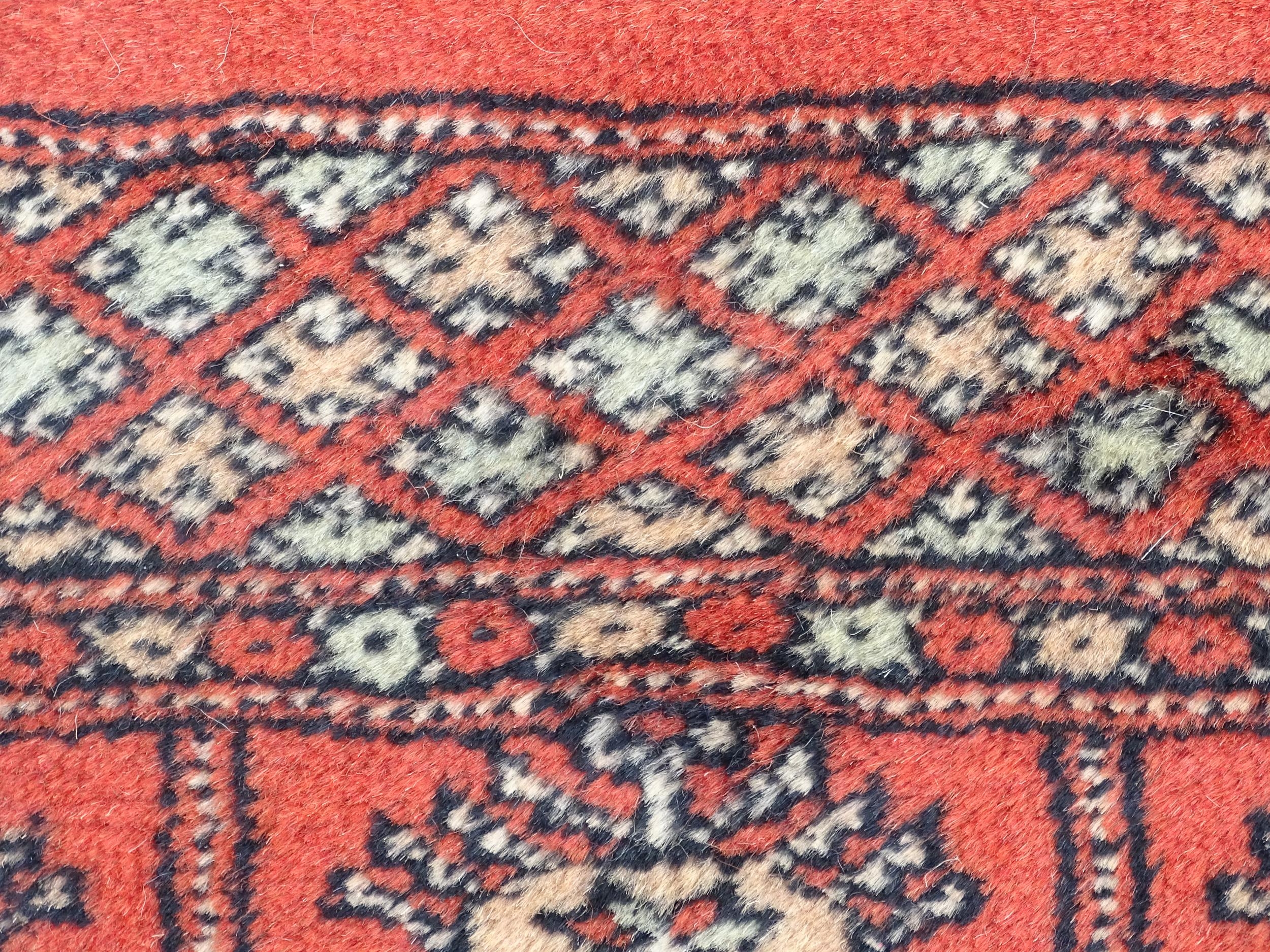Carpet / Rug : A Pakistan wool red ground rug decorated with repeating geometric motifs with further - Image 7 of 8