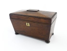 A 19thC rosewood tea caddy of sarcophagus form with four squat bun feet. The interior with two