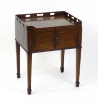 An 18thC mahogany bedside table / tray top cabinet with a pierced upstand above two hinged doors and