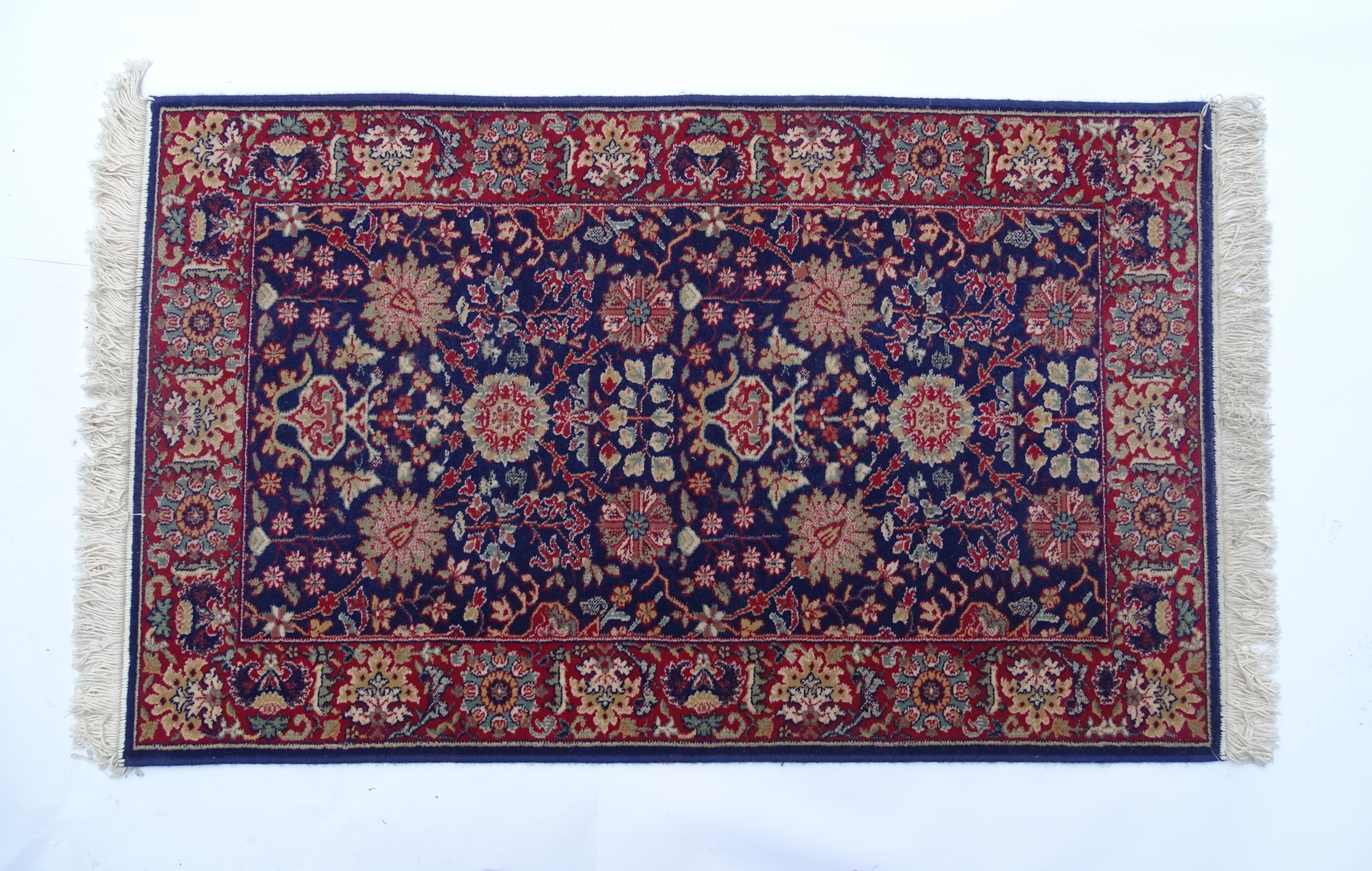 Carpet / Rug : A blue ground wool rug decorated with floral and foliate detail, further repeated