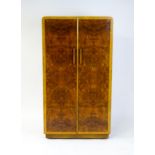 A mid 20thC Art Deco style wardrobe / cupboard with burr walnut veneered doors and shaped handles.