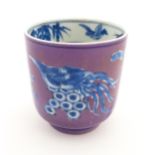 A Chinese cup with a purple ground decorated with birds, foliage and stylised clouds. Character