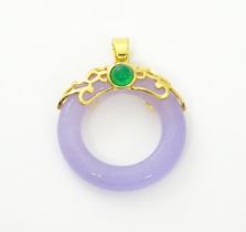 A pendant with gilt metal mounts and purple coloured jade like ring detail. 1 1/2" long Please