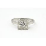A platinum ring set with central diamond flanked by four diamonds in a squared setting, approx 1/