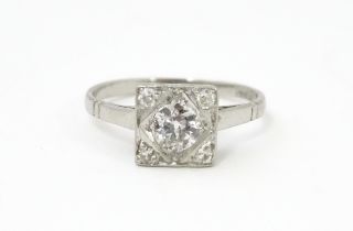 A platinum ring set with central diamond flanked by four diamonds in a squared setting, approx 1/