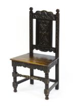 A 19thC carved oak side chair with floral carving, a planked seat and raised on block and turned