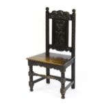 A 19thC carved oak side chair with floral carving, a planked seat and raised on block and turned