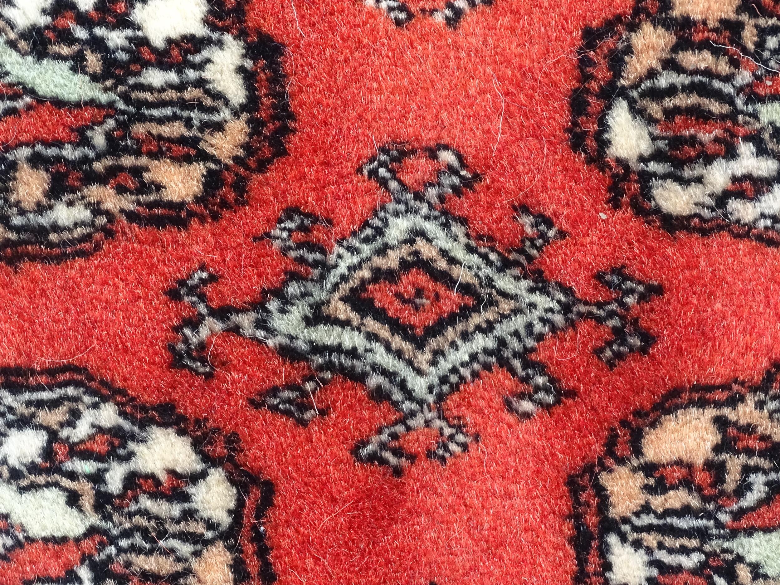 Carpet / Rug : A Pakistan wool red ground rug decorated with repeating geometric motifs with further - Image 6 of 8