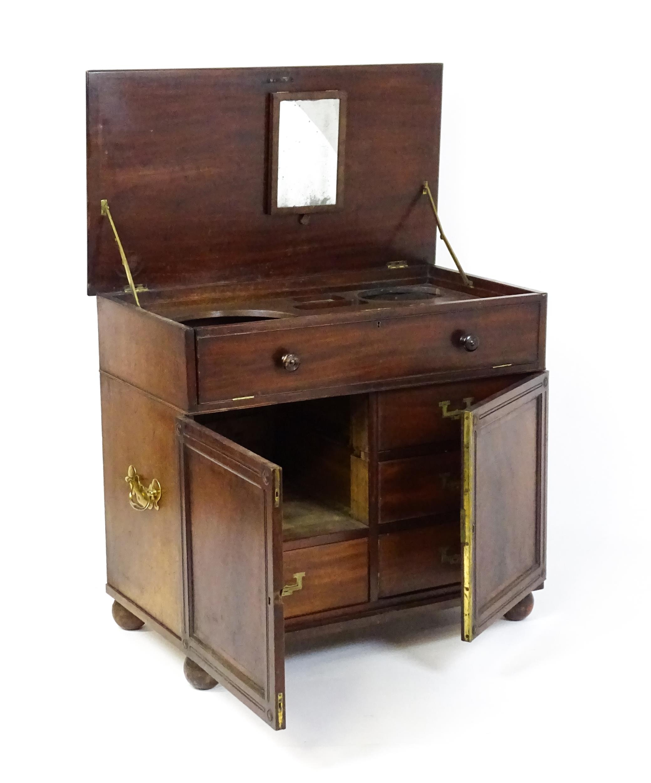 A Georgian mahogany campaign washstand with a mirror to the interior and sections for internal