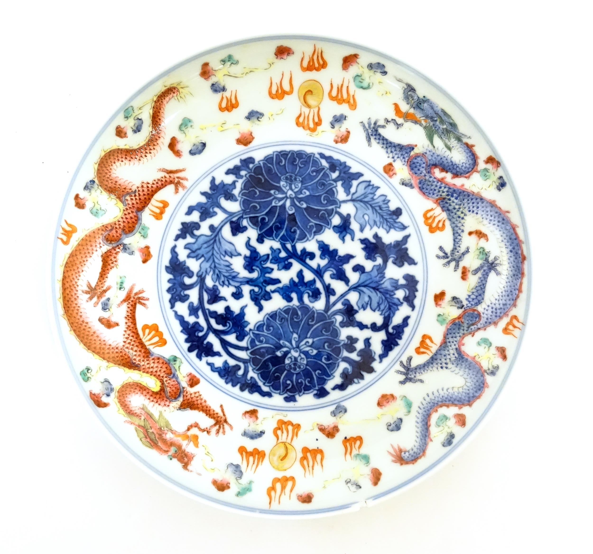 A Chinese dish decorated with central floral and foliate detail bordered by dragons and flaming