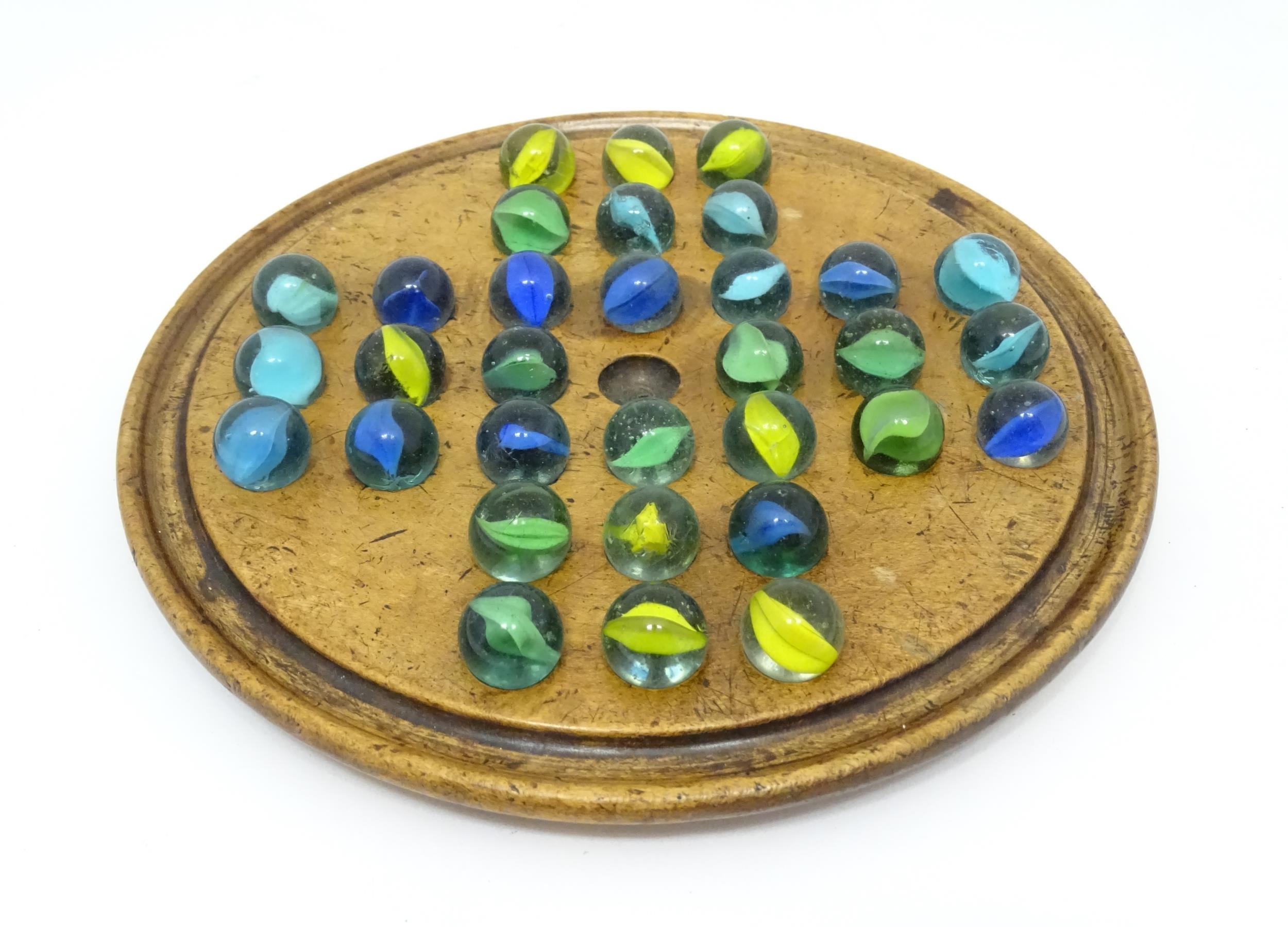 A treen sycamore solitaire board with 32 glass marbles. Board approx. 7 3/4" diameter Please