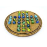 A treen sycamore solitaire board with 32 glass marbles. Board approx. 7 3/4" diameter Please