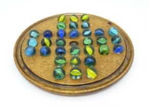 A treen sycamore solitaire board with 32 glass marbles. Board approx. 7 3/4" diameter Please