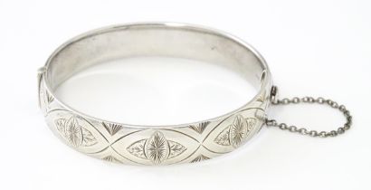 A silver bracelet of bangle form with engraved decoration hallmarked 1963 maker Charles S Green & Co
