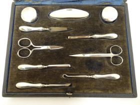 A cased manicure set / necessaire containing silver mounted pots, nail buffer, file, tweezers,