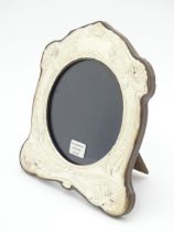 An easel back photograph frame with silver surround with Art Nouveau style decoration depicting