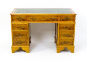 A yew wood veneered double pedestal desk with a gold tooled green leather top above a long central