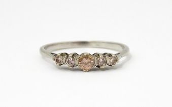A white gold ring set with central brown diamond flanked by 4 further diamonds in a linear